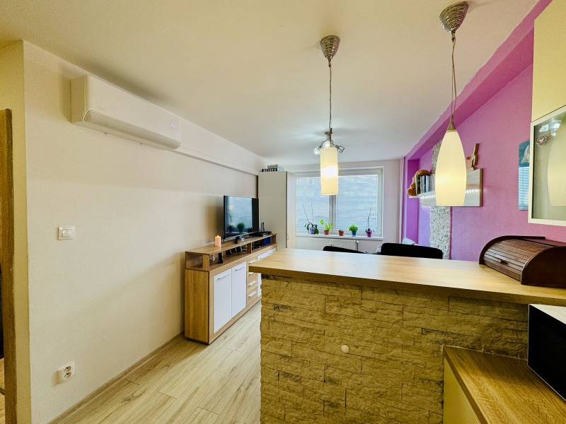 A kitchen in a 2-room apartment with a bar counter, a television, and decorative lamps.