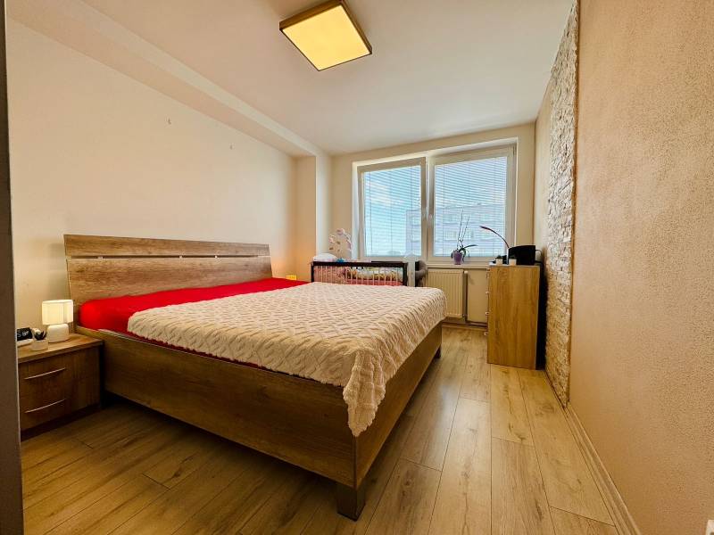 A bedroom in a two-room apartment with a comfortable bed and wooden floors.