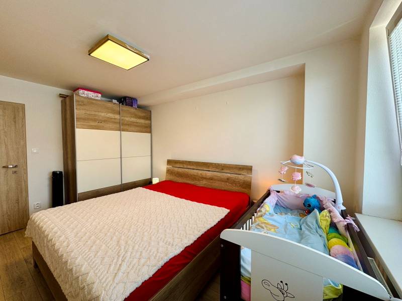 Bedroom in a two-room apartment with a double bed, wardrobe, and baby crib.