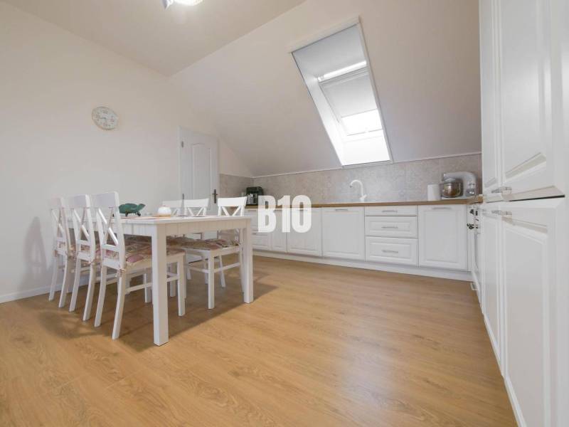 Dining room in a 3-room apartment with a dining table, chairs, and a kitchen unit.