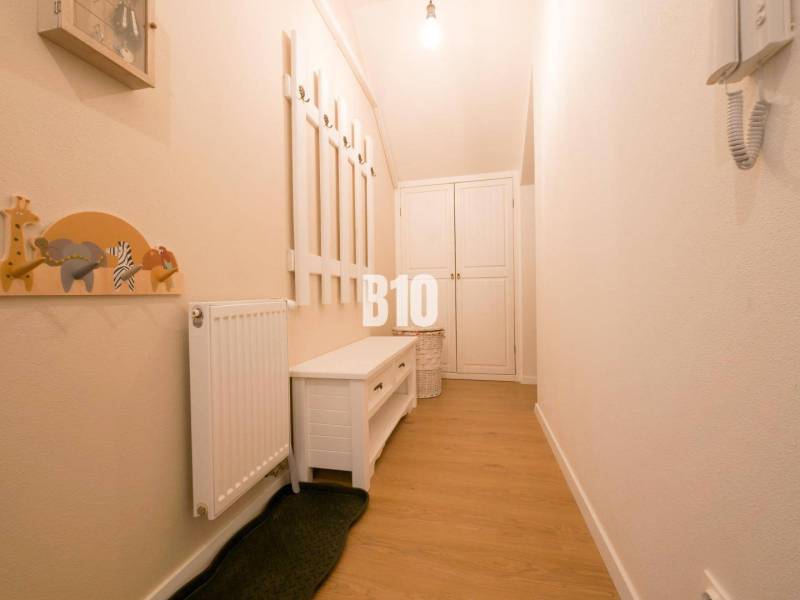 A narrow hallway in a 3-room apartment with a coat rack, a bench, and cabinets on a light floor.