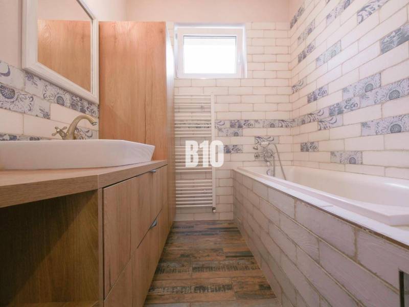 A bathroom in a 3-room apartment with a bathtub, a sink, and decorative tiles.