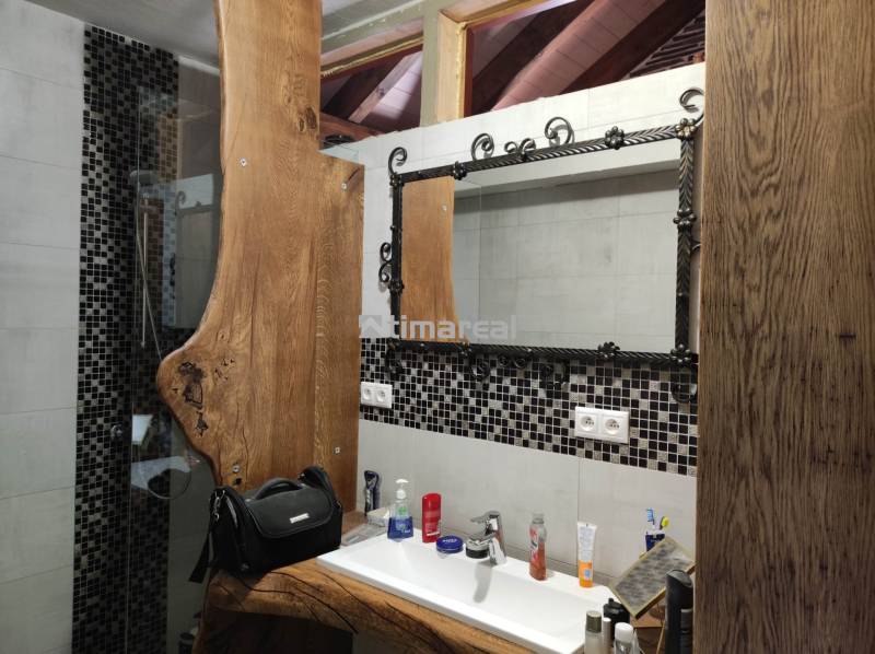 A bathroom in a 2-room apartment with a wooden sink table and a mirror with a metal frame.
