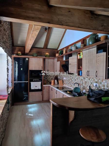 A wooden kitchen in a two-room apartment with stone details and wooden beams.