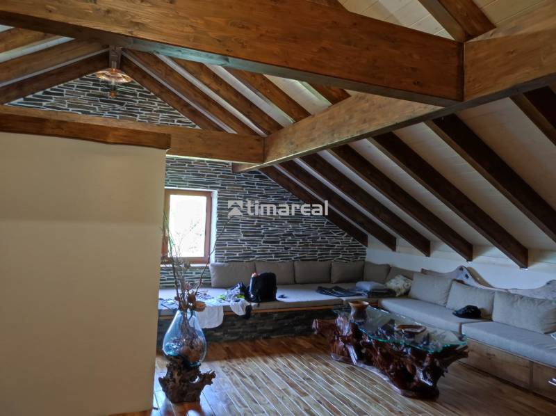 Beam ceiling in a 2-room apartment with a sofa and a wooden table.