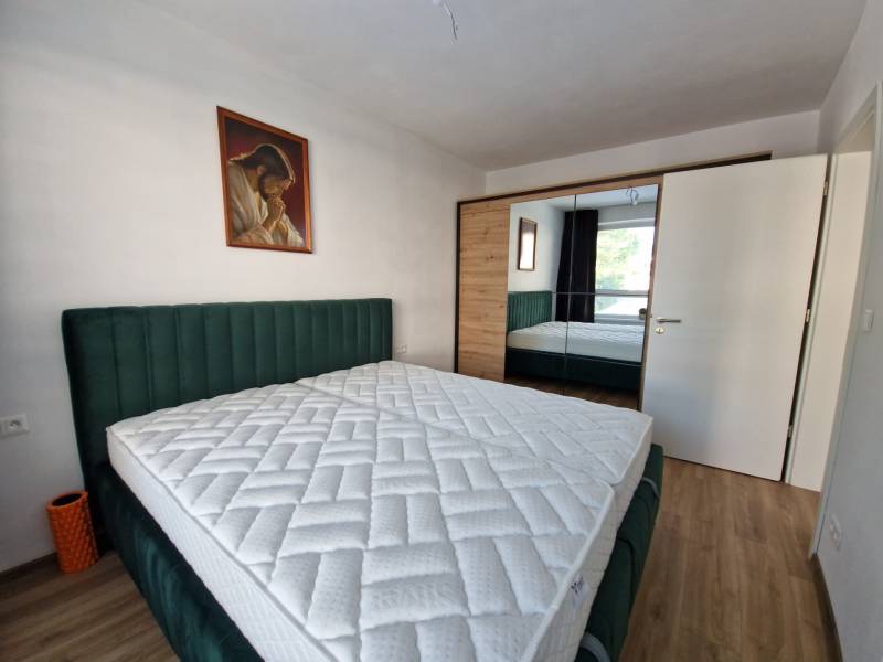 Bedroom in a two-room apartment with a double bed, painting, and built-in wardrobe.