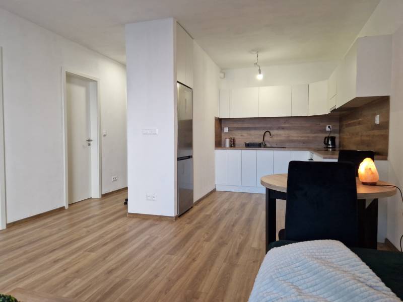Kitchen and dining area in a 2-room apartment with wooden flooring and white furniture.