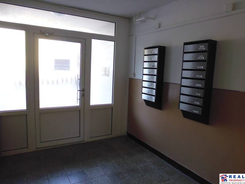Entrance to an apartment building with mailboxes and glass doors.