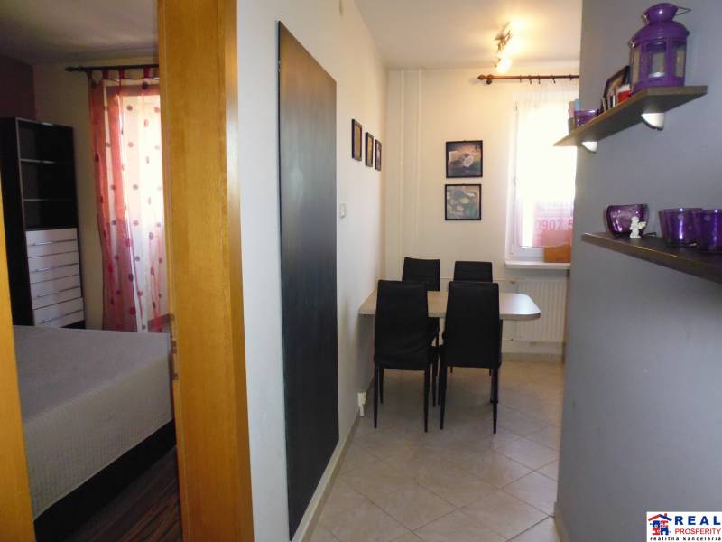 Dining area with chairs and a shelf in the entrance of a 3-room apartment.