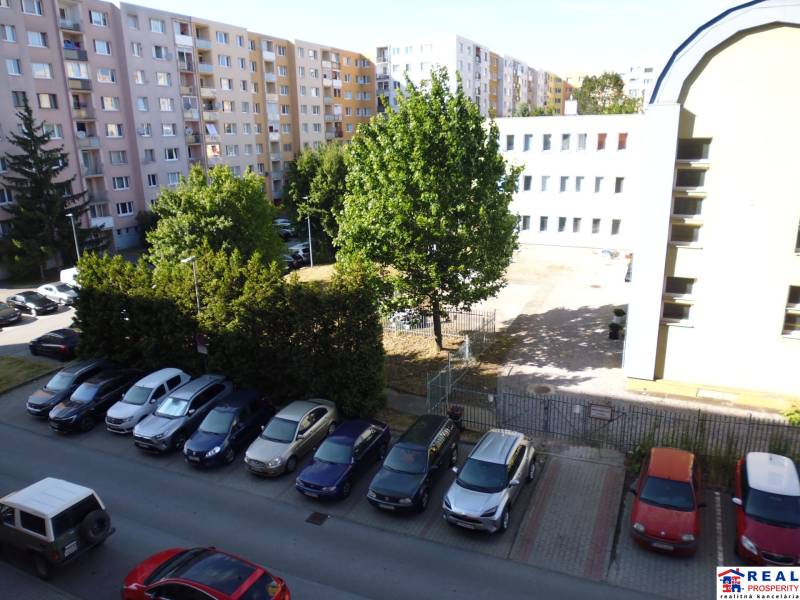 Parking lot and apartment buildings on Lomnická Street in Prešov, surrounded by greenery.