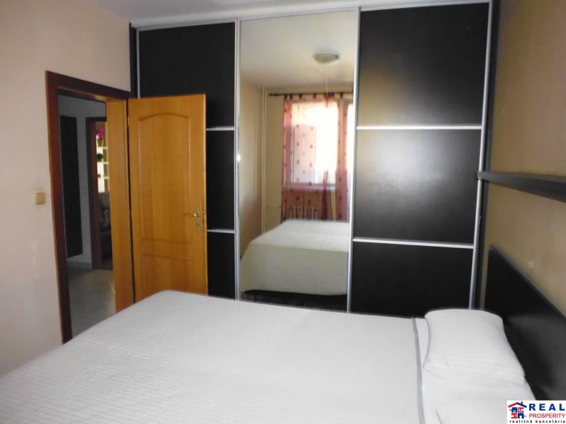 Wardrobe in the bedroom of a 3-room apartment with a bed and a mirror on the door.