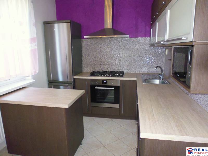 A kitchen with stainless steel appliances and a purple wall in a 3-room apartment.