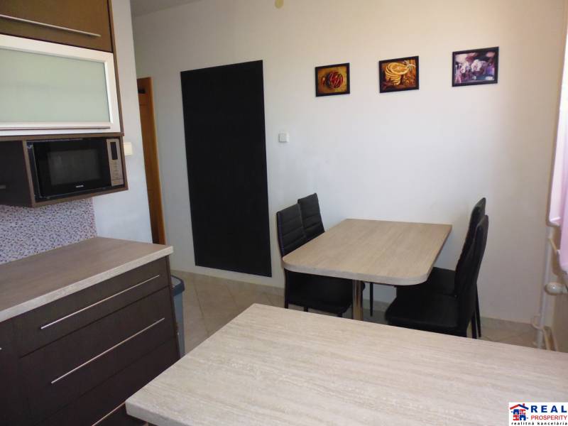 Dining area with dark furniture and pictures on the wall in a 3-room apartment.