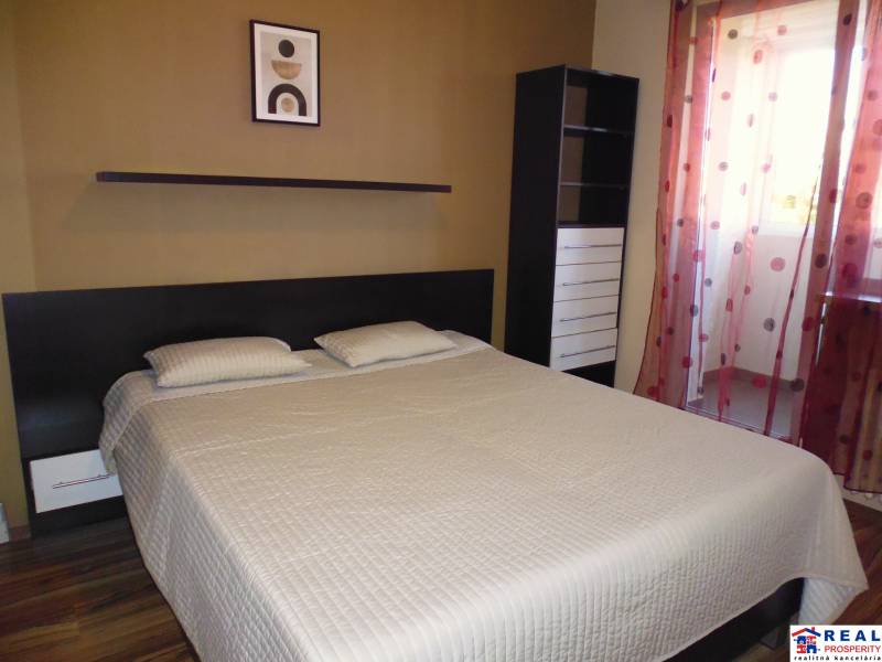 Bedroom in a 3-room apartment with a bed, shelf, and drawers behind a curtain.
