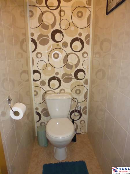 A toilet with decorative wallpaper and tiles in a 3-room apartment.