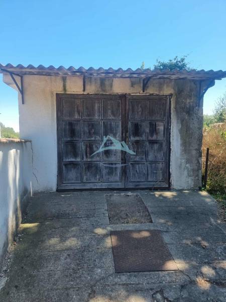 An older garage behind a family house in Ipolyvece with a metal roof and wooden doors.
