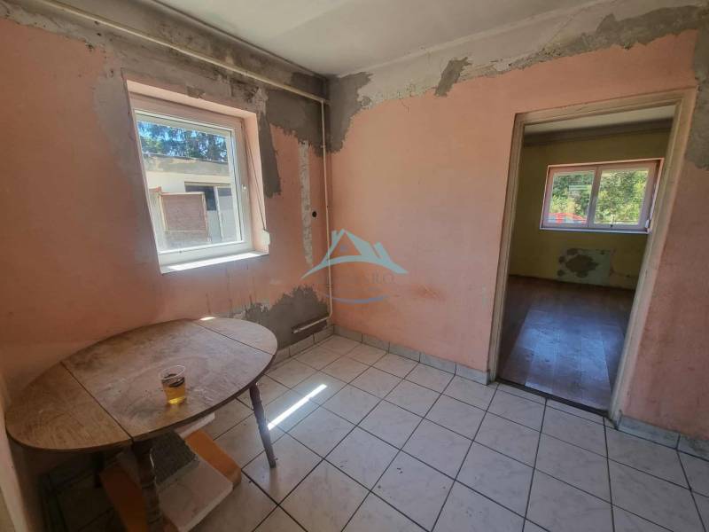 A room in a family house with a window, visible are worn-out walls and an old table.
