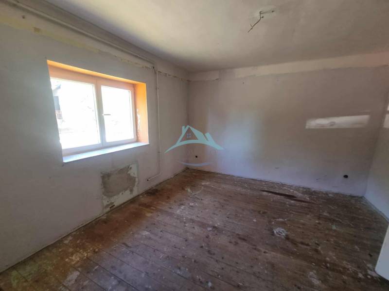 A room in a family house with a wooden floor and a large window.