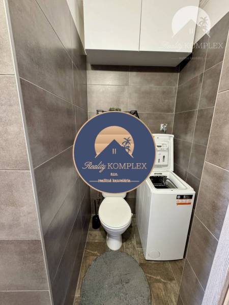 WC with a washing machine in a 4-room apartment, tiled with gray tiles and storage cabinets.