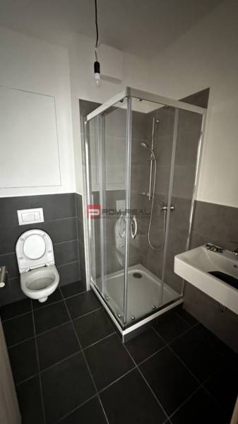 Bathroom with a toilet, shower, and sink in a 2-room apartment.