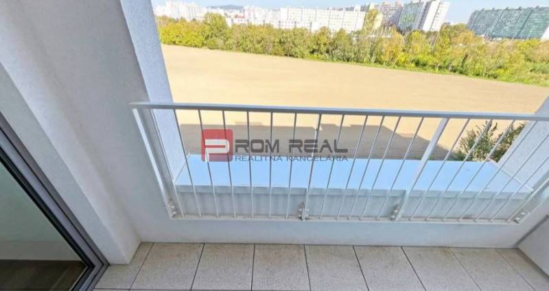 The balcony of a 2-room apartment on Labutia Street, Bratislava V with a view of greenery and buildings.