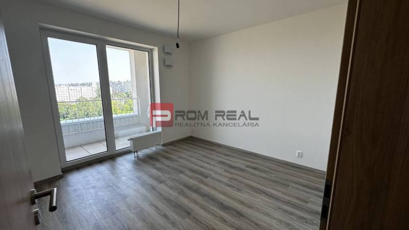 An empty room with laminate flooring and glass doors in a two-room apartment.
