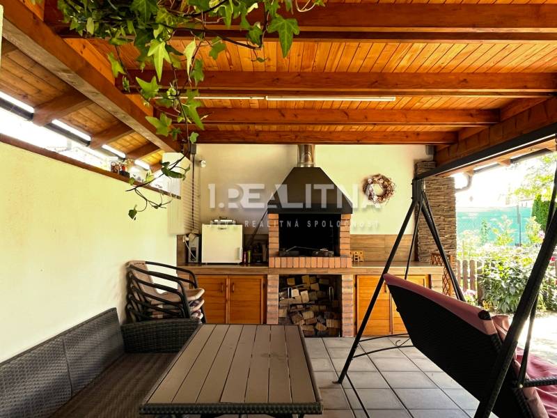 Covered terrace with a fireplace and a swing in a family house.
