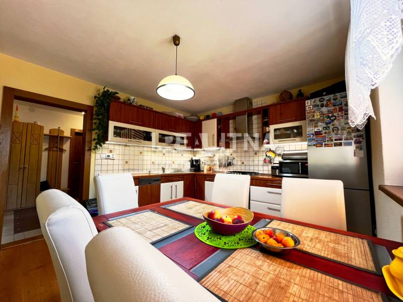 Kitchen in a family house with a dining table, chairs, and appliances.