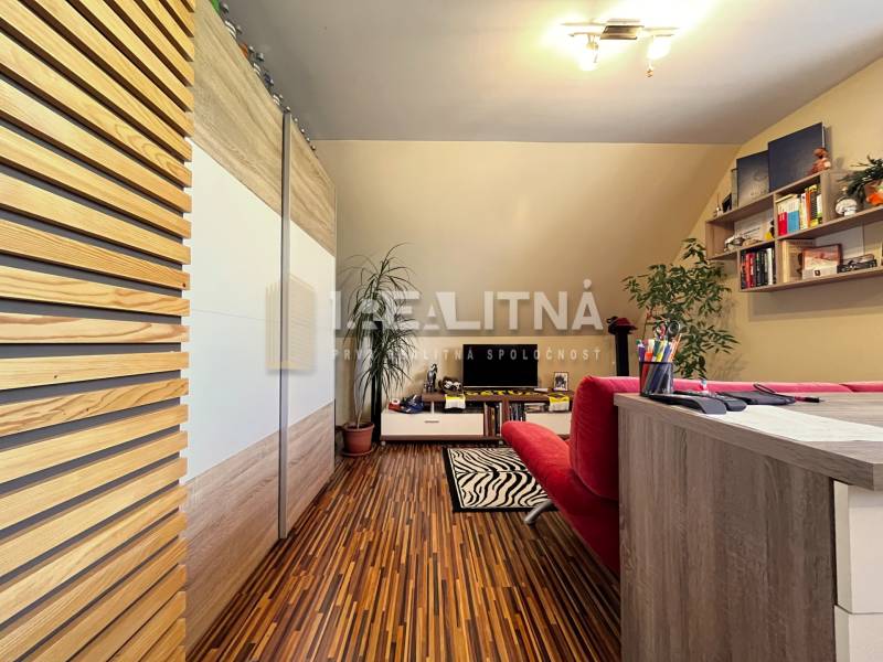 Office with wooden floor, red sofa, and desk, family house.