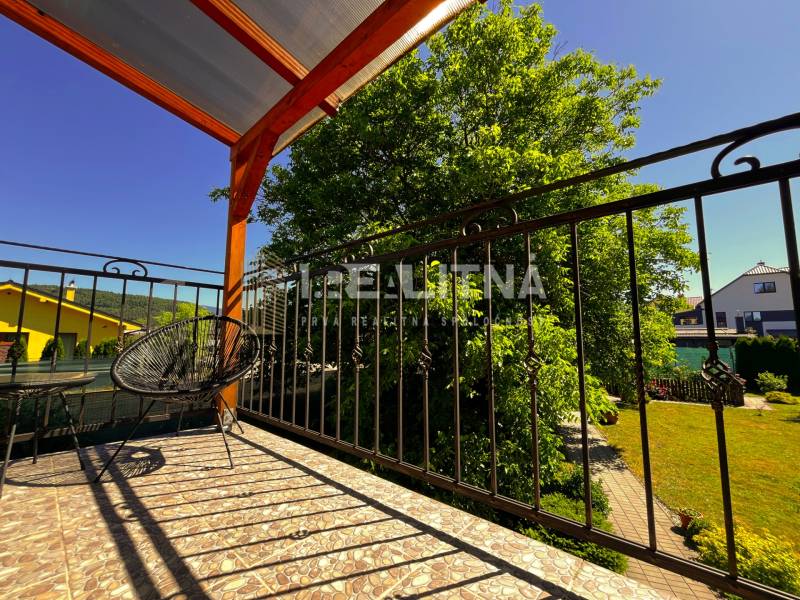 The balcony of a family house in Kriváň with a view of the garden and blue sky.