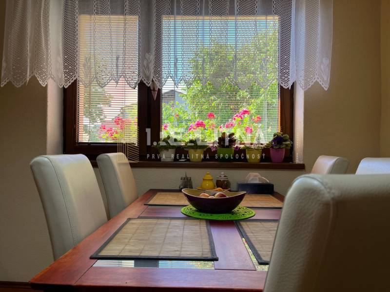 The dining room in the family house with a window and flowers offers a pleasant view outside.