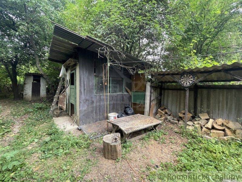 A wooden garden house with a shed in the yard of a family home in Branč.