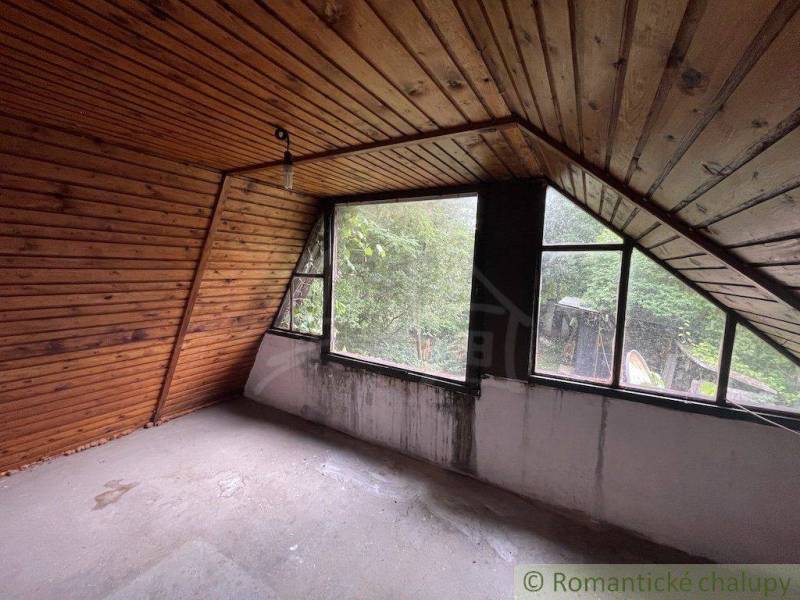 Attic room in a family house with wooden paneling and large windows.