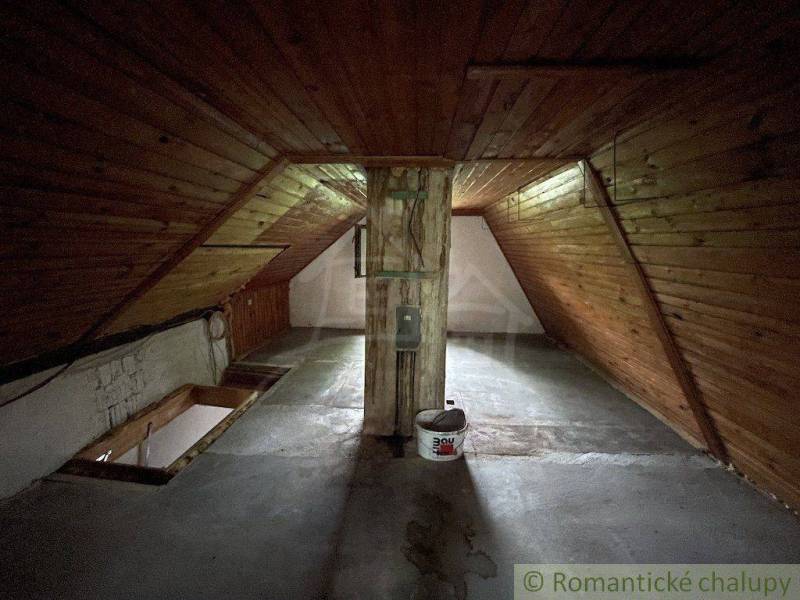 An attic with wooden paneling and a concrete floor in a family house.