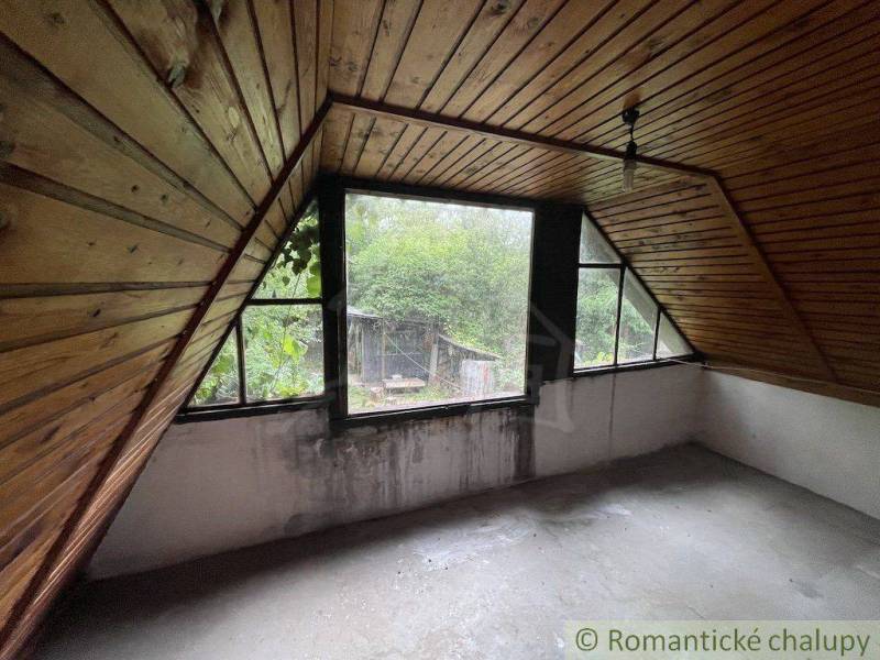 Attic room in a family house with wooden paneling and a view of the garden.