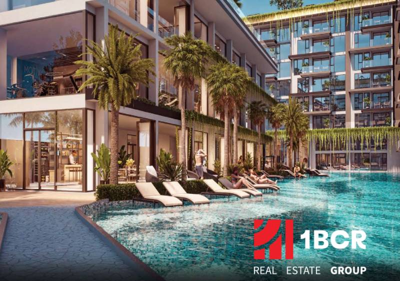 Apartment construction in Pattaya with a pool and loungers surrounded by palm trees and plants.