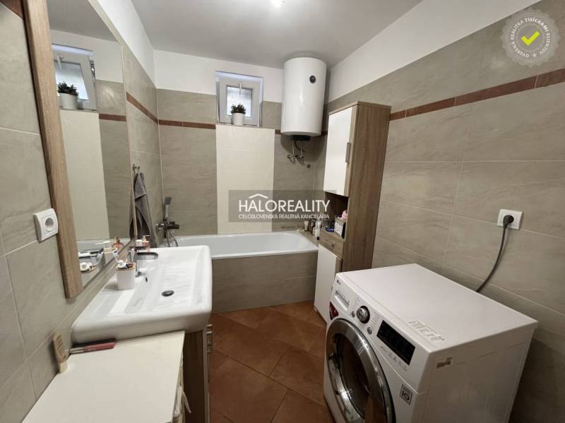 A bathroom in a family house with a shower, washing machine, and sink.