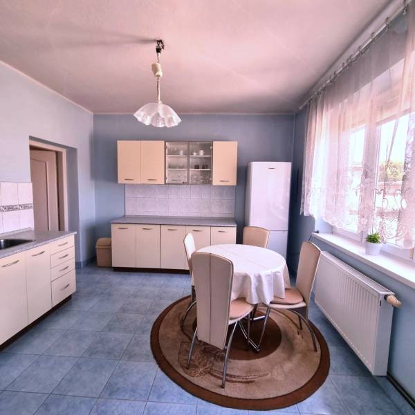 A kitchen in a family house with a dining table, kitchen unit, and refrigerator.