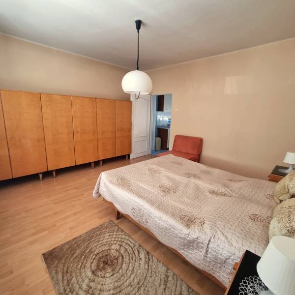 Bedroom in a family house with a bed, wardrobe, and chair on a light floor.