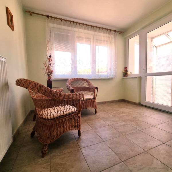 Two wicker chairs with cushions in a sunlit room of a family house.