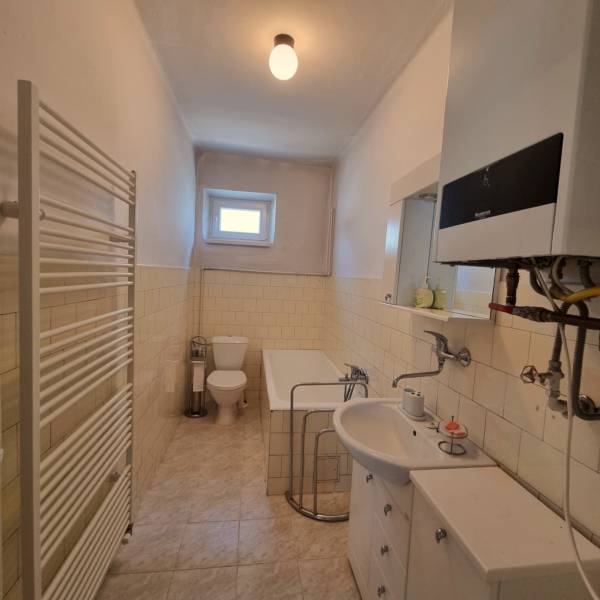 A bathroom in a family house with a bathtub, toilet, and sink in light shades.