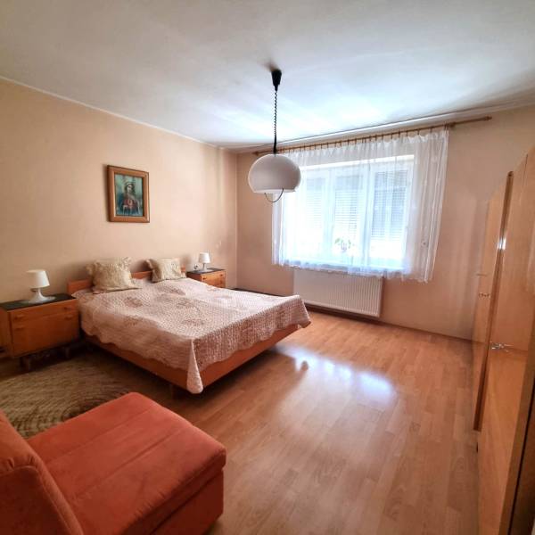 A bedroom in a family house with a double bed, a painting, and a large window.
