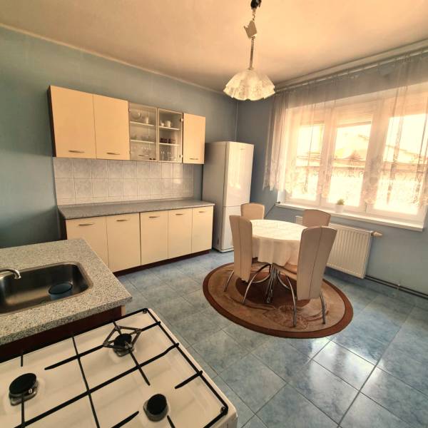 Kitchen in a family house with a dining table, kitchen unit, and electric stove.
