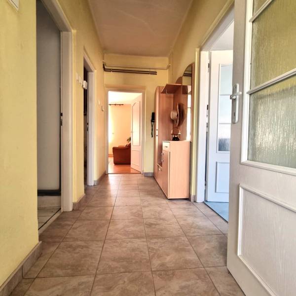A hallway of a family house with tiles, doors, and storage furniture.