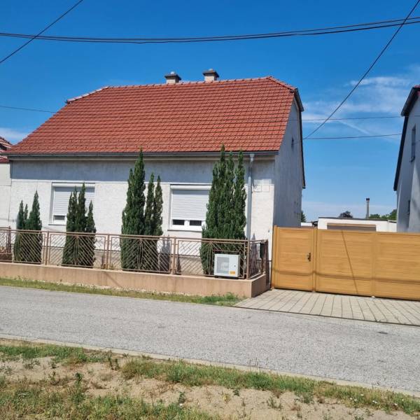 A family house on Riadok in Malacky with a red roof, a front garden, and a wooden gate.