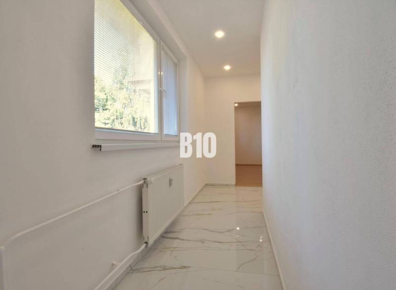 A hallway in a 3-room apartment with marble flooring and a window with a view.