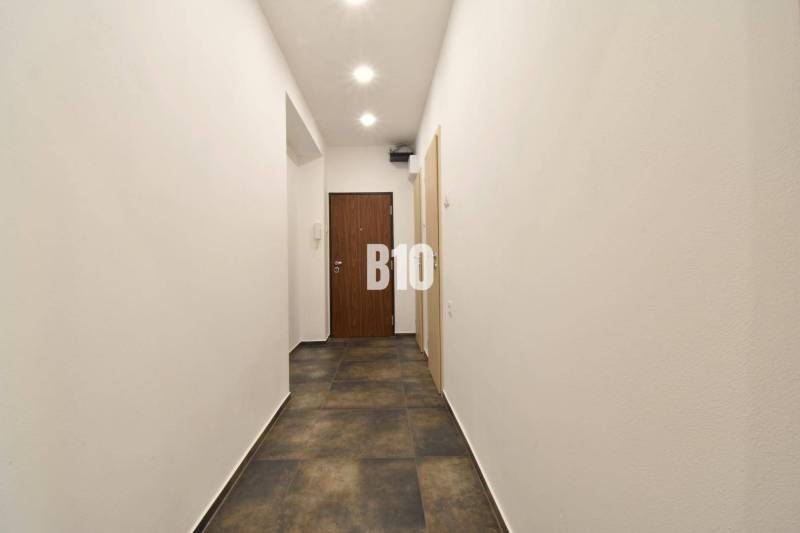 A hallway with white walls and a dark floor in a 3-room apartment.