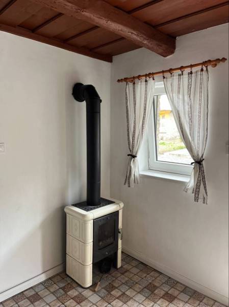 A bathroom in a family house with a tiled floor and a window with sheer curtains.