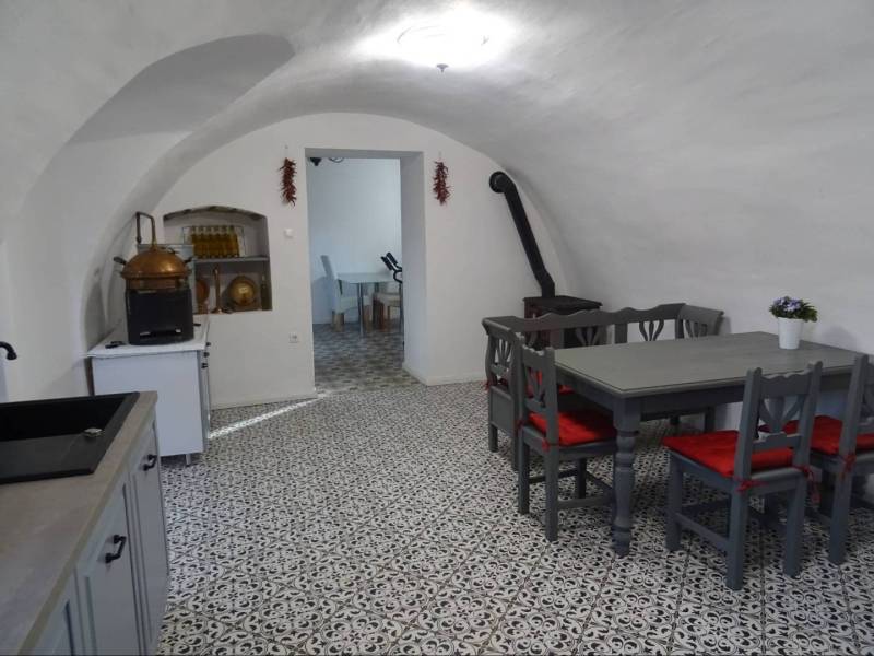 Interior of a family house with a vaulted ceiling, tiled floor, and dining table.