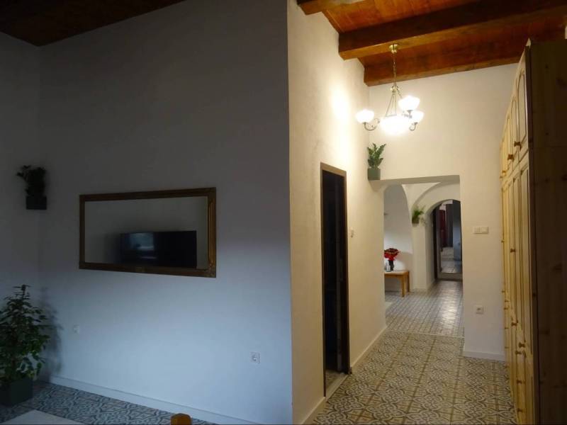 Interior of a family house with wooden ceilings, patterned floor, and a mirror on the wall.